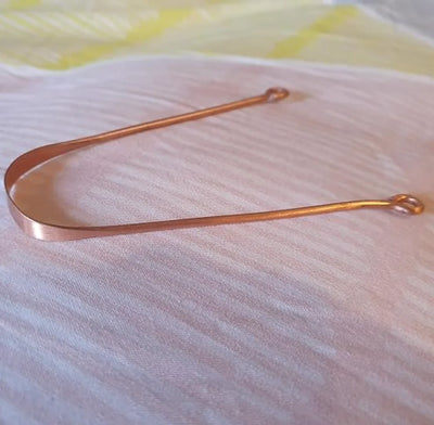 Copper tongue scraper in use - removing bacteria for bad breath prevention