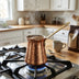 Copper coffee warmer on stovetop for heating coffee milk and chai